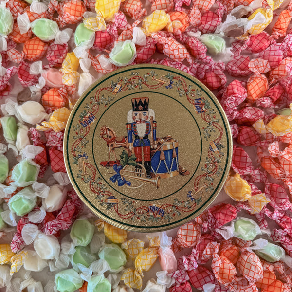 Decorative tin with a nutcracker design surrounded by colorful taffy.